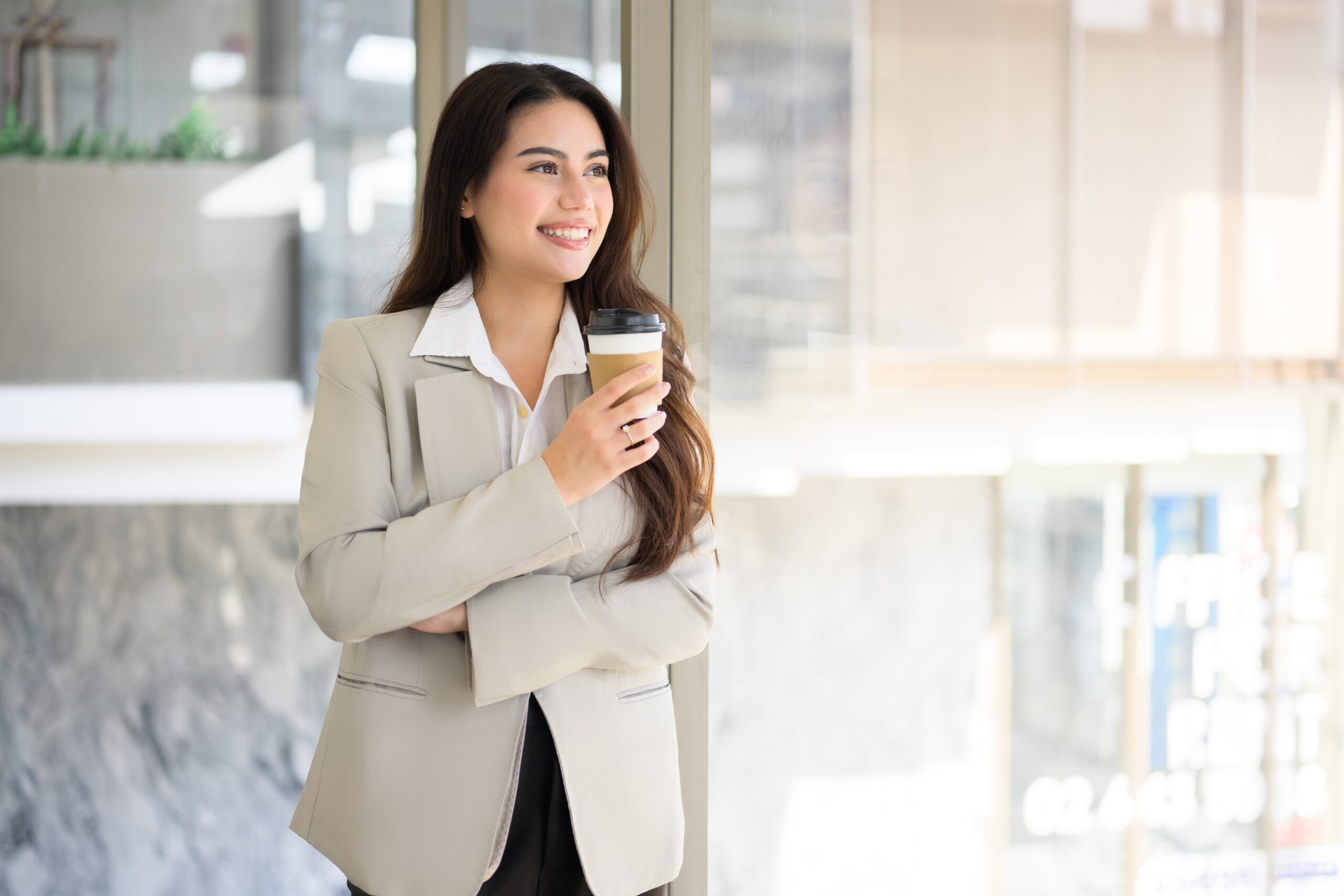 Person smiling as they walk into an office holding a cup of coffee, symbolizing a confident return to work after rehab Person confidently returning to work after addiction treatment
